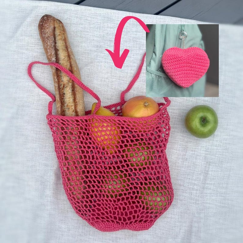 Puede incluir: Una bolsa de red rosa tejida a ganchillo llena de una baguette, limones y manzanas. Una manzana verde est&aacute; al lado de la bolsa. Tambi&eacute;n se muestra un llavero en forma de coraz&oacute;n rosa tejido a ganchillo. La bolsa tiene asas largas.