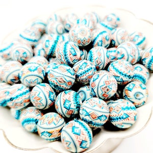 May include: A bowl filled with white, blue, and orange patterned round beads. The beads have a geometric design.