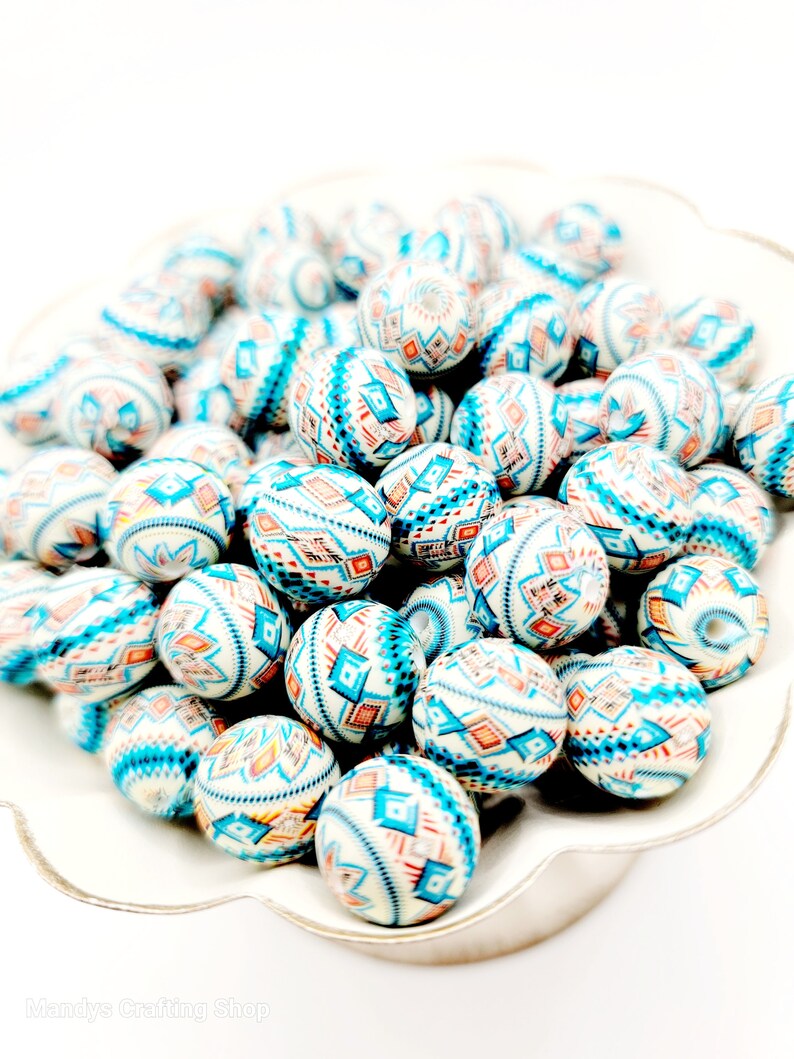 May include: A bowl filled with white, blue, and orange patterned round beads. The beads have a geometric design.