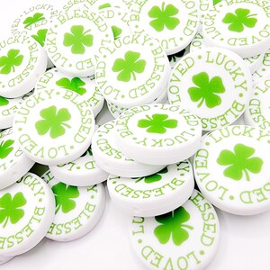 Peut inclure: Perles rondes blanches avec des tr&egrave;fles &agrave; quatre feuilles verts et les mots "Lucky", "Blessed" et "Loved" imprim&eacute;s dessus.