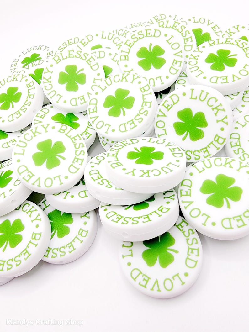 Peut inclure: Perles rondes blanches avec des tr&egrave;fles &agrave; quatre feuilles verts et les mots "Lucky", "Blessed" et "Loved" imprim&eacute;s dessus.