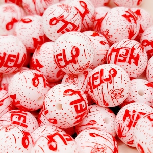 May include: A close-up of a pile of white silicone beads with red lettering that says "HELP". The beads have a speckled texture and are perfect for making jewelry or other crafts.