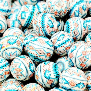 May include: A close-up of a pile of white, blue, and orange round beads with a geometric pattern. The beads are made of plastic or ceramic and are perfect for jewelry making.