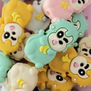 May include: A collection of colorful silicone animal charms with cute faces. The charms are in various colors, including yellow, blue, pink, and gray. Each charm features a different animal, such as a bear, a monkey, and a rabbit.