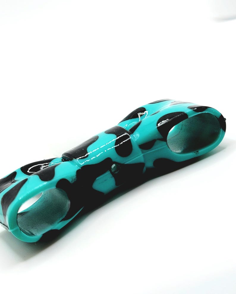 May include: A teal and black patterned object with a curved design. The object has a glossy finish and a camouflage-like pattern. The object has two circular openings on either end.