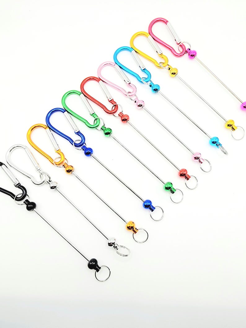 Op de afbeelding: Assortiment van kleurrijke metalen sleutelhangers met een karabijnhaak en een metalen bal aan een lange metalen ketting.