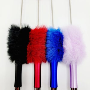 May include: Four furry pens with different coloured fur and metal tips. The pens are black, red, blue, and purple.