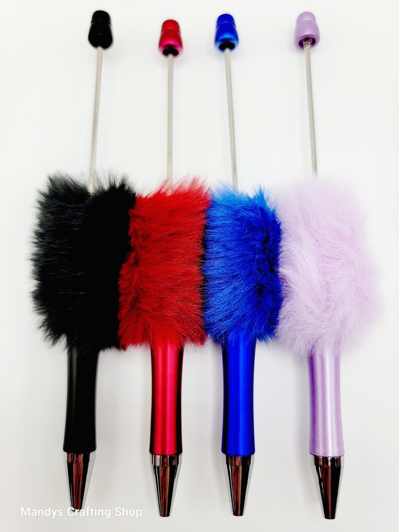 May include: Four furry pens with different coloured fur and metal tips. The pens are black, red, blue, and purple.