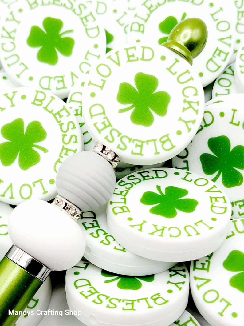 Peut inclure: Gros plan sur un tas de rondins de c&eacute;ramique blancs avec des tr&egrave;fles &agrave; quatre feuilles verts et les mots "Blessed", "Loved" et "Lucky" imprim&eacute;s dessus.