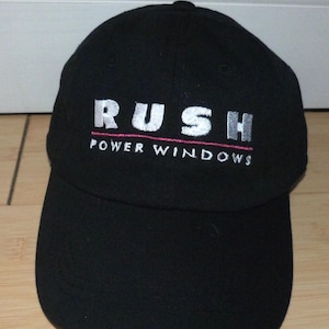 May include: Black baseball cap with a white embroidered logo that says "RUSH POWER WINDOWS".
