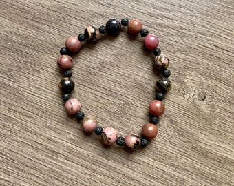 May include: A bracelet made of pink and black beads. The beads are round and have a smooth texture. The bracelet is made of natural stones.