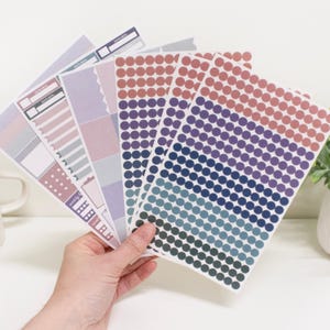 Puede incluir: Un conjunto de pegatinas para planificadores con una variedad de diseños. Las pegatinas presentan un degradado de colores azul, morado y rosa. Las pegatinas son perfectas para agregar un toque de color y personalidad a tu planificador.