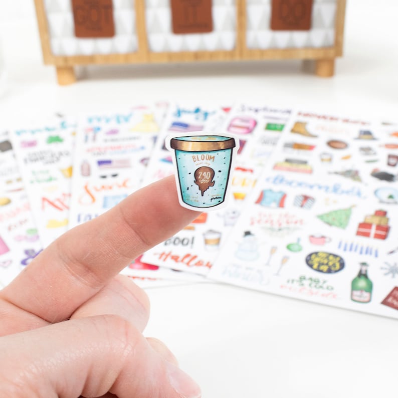 May include: A sticker of a blue and white ice cream container with the text "BLOOM" and "240 ml" on it. The sticker is part of a set of stickers with various designs.