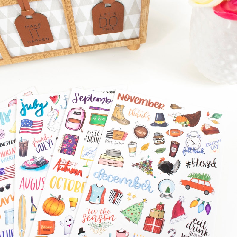 May include: A set of colorful monthly planner stickers featuring illustrations of various themes for each month, including a unicorn for July, a school backpack for September, a turkey for November, and a Christmas tree for December.