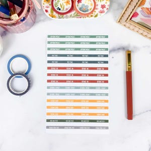 May include: A rectangular sheet of adhesive planner stickers featuring rows of color-coded labels with text including Appointment, Meeting, Bring In, School Event, Theme Day, Volunteer, and Donation Due, arranged in a grid on a white background.