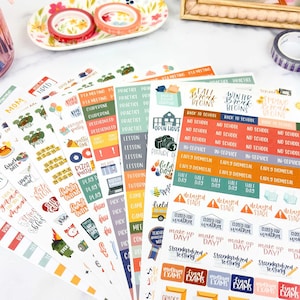 May include: Multiple sheets of adhesive planner stickers featuring various school-related themes, including text labels like Fall Break Begins, No School, Early Dismissal, and Standardized Testing, alongside colorful icons of school buses and cameras.
