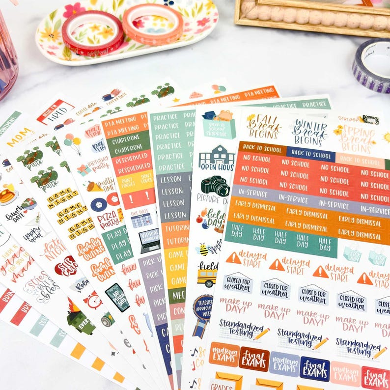 May include: Multiple sheets of adhesive planner stickers featuring various school-related themes, including text labels like Fall Break Begins, No School, Early Dismissal, and Standardized Testing, alongside colorful icons of school buses and cameras.