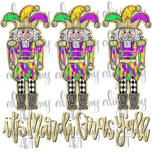 May include: Three Mardi Gras-themed nutcrackers with yellow, green, and purple jester hats and outfits. The nutcrackers have white hair and mustaches, black and white checkered pants, and gray boots. The text "it's Mardi Gras Y'all" is below.
