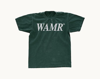 May include: A dark forest green short-sleeve t-shirt featuring the text WAMR in a white serif font across the chest. The garment has a crew neckline and a standard fit, with a small registered trademark symbol positioned next to the text.