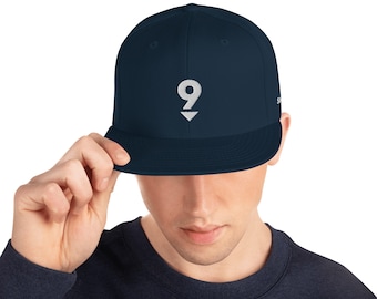 Könnte beinhalten: Eine marineblaue Baseballkappe mit einer weißen gestickten Nummer 9 auf der Vorderseite.