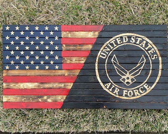 Puede incluir: Una bandera americana de madera con un acabado desgastado, que presenta el emblema de la Fuerza Aérea de los Estados Unidos en dorado sobre un fondo negro.
