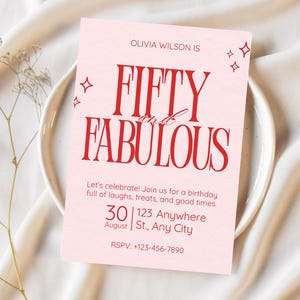 Könnte beinhalten: Eine rosa Geburtstagseinladungskarte mit rotem Text "FIFTY and FABULOUS". Die Karte enthält Datum, Uhrzeit und Ort sowie dekorative Sternchen. Die Karte liegt auf einem weißen Teller.