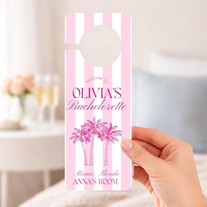 May include: A rectangular door hanger with a pink and white vertical striped pattern. The text reads WELCOME TO OLIVIA'S Bachelorette, Miami, Florida, ANNA'S ROOM. Below the text is a graphic illustration of three palm trees in dark pink.