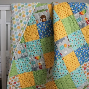 May include: A patchwork baby quilt with a variety of animal and geometric patterns in shades of blue, green, yellow, and gray. The quilt is made of soft cotton fabric and is perfect for cuddling.