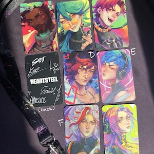 Może przedstawiać: Zestaw sześciu kolorowych kart z ilustracjami postaci w stylu anime. Karty są oznaczone literami od A do F i są częścią zestawu o nazwie "HEARTSTEEL" z napisem "SET EXCLUSIVE" umieszczonym pod kartami.