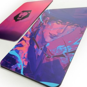 May include: Two rectangular cards with rounded corners. One card features a stylized portrait in shades of purple, blue, and orange. The other card has a gradient background of pink and purple with a black lion emblem.
