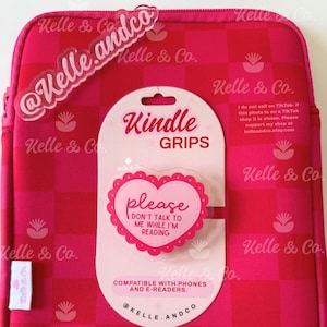 May include: A pink and red checkered Kindle sleeve with a matching pop-up grip. The grip is heart-shaped and says "Please don't talk to me while I'm reading." The sleeve and grip are compatible with phones and e-readers.
