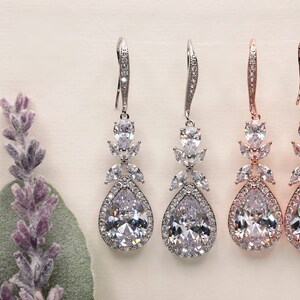 May include: Three pairs of teardrop-shaped dangle earrings with crystal accents. The earrings are available in silver, rose gold, and gold finishes.