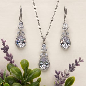 May include: A silver bridal jewelry set with a teardrop pendant necklace and matching earrings. The set features clear cubic zirconia stones.