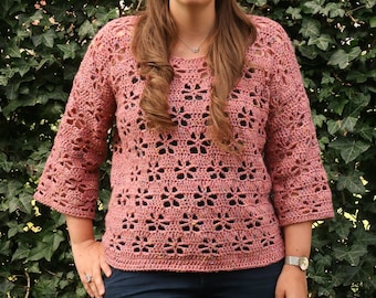Puede incluir: Un top de crochet con un delicado patrón de calado en color rosa polvoriento. El top tiene un corte holgado y mangas tres cuartos.