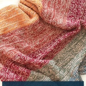 Pode incluir: Uma manta de crochê multicolorida com um degradê de cores azul, verde, vermelho e laranja. A manta está dobrada ao meio e o texto "BLANKET CROCHET PATTERN" é exibido em um fundo azul.