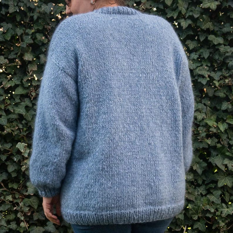 May include: A soft, light blue knitted jumper with a crew neck.