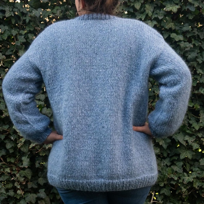 May include: A light blue knitted jumper with long sleeves.