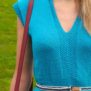 May include: A turquoise blue knitted dress with a v-neck and a white and navy blue braided belt.