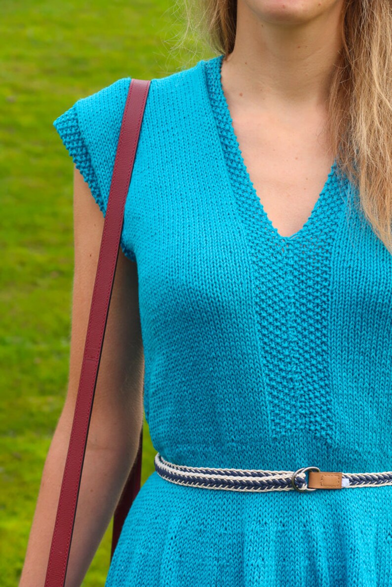 May include: A turquoise blue knitted dress with a v-neck and a white and navy blue braided belt.