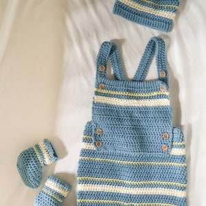 May include: A blue and white striped crocheted baby outfit with matching hat and booties. The outfit features a crocheted bib and straps.