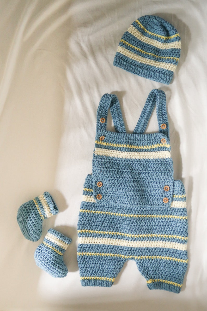 May include: A blue and white striped crocheted baby outfit with matching hat and booties. The outfit features a crocheted bib and straps.