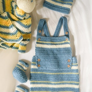 May include: A blue and white striped crocheted baby outfit with a matching hat and booties. The outfit includes a pair of overalls and a hat. The booties are also striped in blue and white.