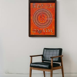 Pu&ograve; includere: Un'opera d'arte murale rettangolare in una cornice marrone scuro con uno sfondo arancione vibrante e intricate figure tribali bianche in stile Warli. Il design centrale &egrave; un grande motivo a mandala circolare con figure danzanti.