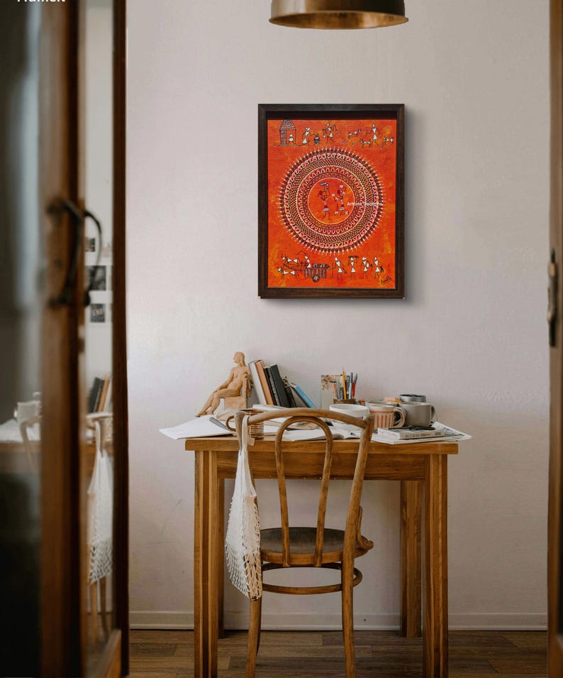 Pu&ograve; includere: Un'opera d'arte da parete rettangolare incorniciata caratterizzata da uno sfondo arancione vibrante con intricati disegni a linee bianche in stile tribale. L'opera mostra un grande motivo mandala circolare centrale circondato da piccole figure di persone e animali.
