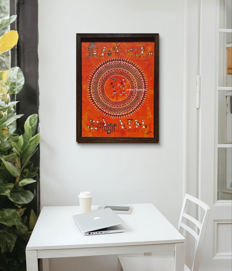 Pu&ograve; includere: Un dipinto rettangolare incorniciato su sfondo arancione con intricate figure bianche in stile Warli disposte in un grande motivo a mandala circolare centrale, con ulteriori piccole scene di persone e animali raffigurate sui bordi superiore e inferiore.
