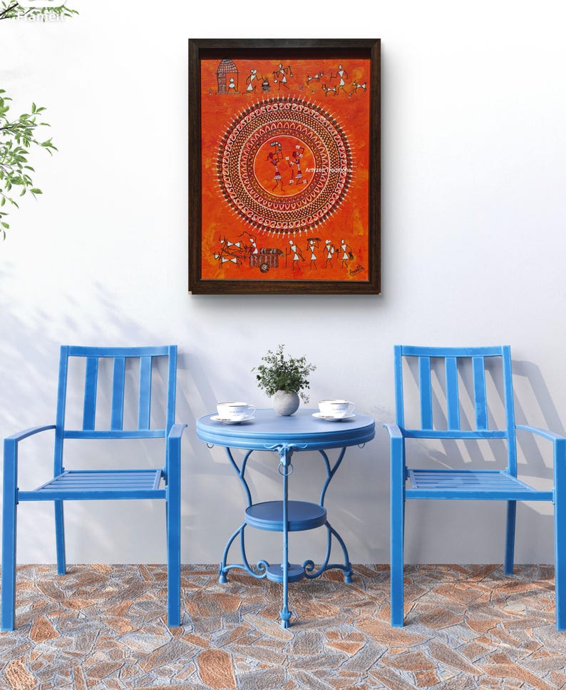 Pu&ograve; includere: Un dipinto rettangolare incorniciato con sfondo arancione che presenta intricate figure tribali bianche e un motivo centrale a mandala circolare. L'opera d'arte &egrave; esposta sopra due sedie in metallo blu brillante e un tavolo rotondo in metallo abbinato.