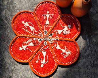 May include: A red, flower-shaped serving tray with six sections, each painted with a white silhouette of a person in a traditional Indian folk art style. The tray is decorated with small white dots and has a textured surface. The text "Artyzen Traditions" is visible in the centre of the tray.