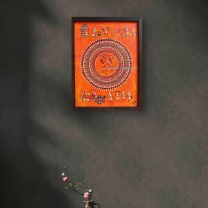 Pu&ograve; includere: Un dipinto rettangolare incorniciato con uno sfondo arancione vibrante e intricate illustrazioni a bastoncino bianche. L'opera mostra un grande motivo mandala circolare centrale circondato da scene pi&ugrave; piccole della vita quotidiana, tra cui figure, animali e un carro.
