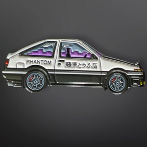 May include: White and black enamel pin of a car with the words "PHANTOM" and "藤原とうふ店" on the side.