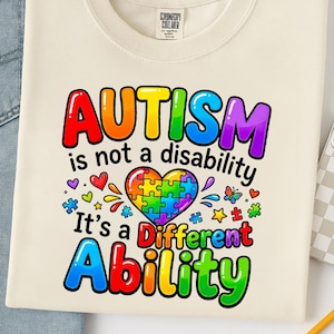 May include: Cream-coloured sweatshirt with the words "AUTISM is not a disability It's a Different Ability" in rainbow colours. The design includes a puzzle heart and other colourful graphics.